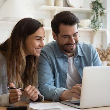 A young couple uses a laptop to check their bank accounts from Patelco Online.